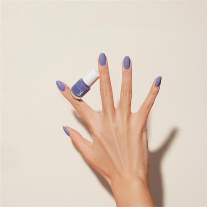 Hand with Periwinkle Passion painted on nails holding mini lacquer bottle