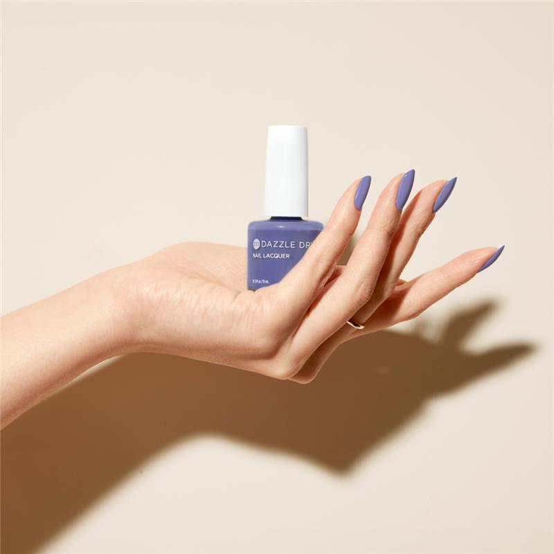 Hand with Periwinkle Passion painted on nails holding lacquer bottle