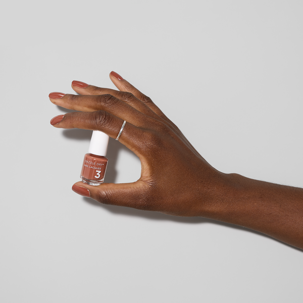 Hand with Argyle painted on nails holding mini lacquer bottle