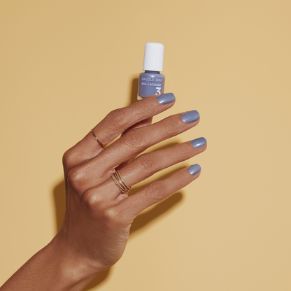 Hand with Blue Moon painted on nails holding mini lacquer bottle