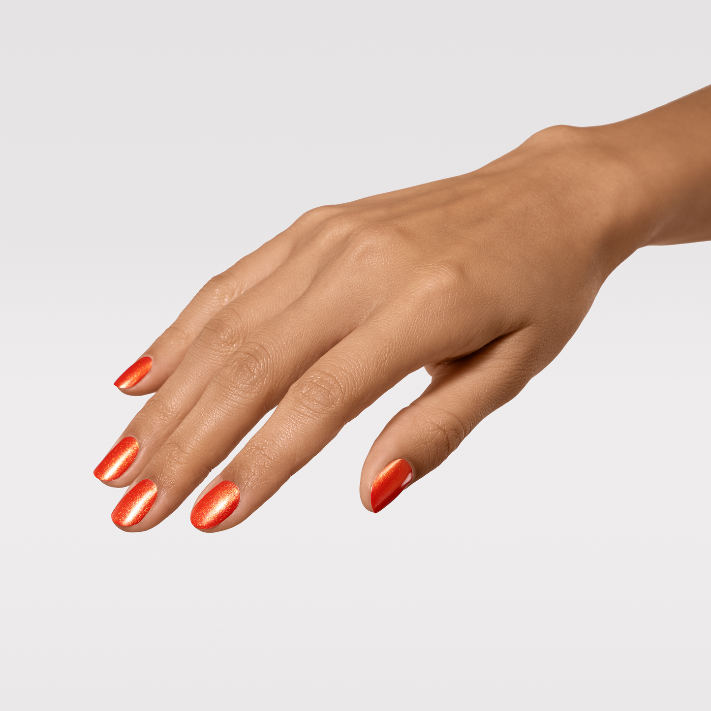 Hand with orange nail polish on a light gray background