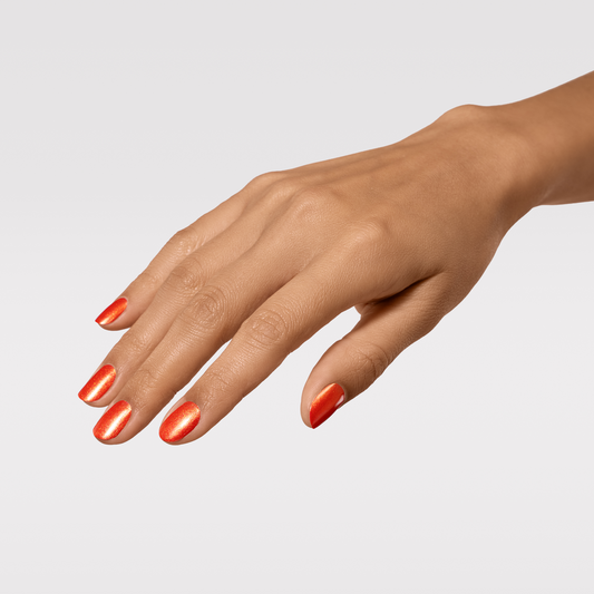 Hand with orange nail polish on a light gray background