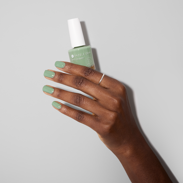 Hand with Cardigan painted on nails holding lacquer bottle