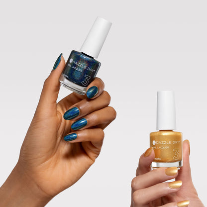 Two hands holding bottles of Dazzle City nail polish against a light gray background