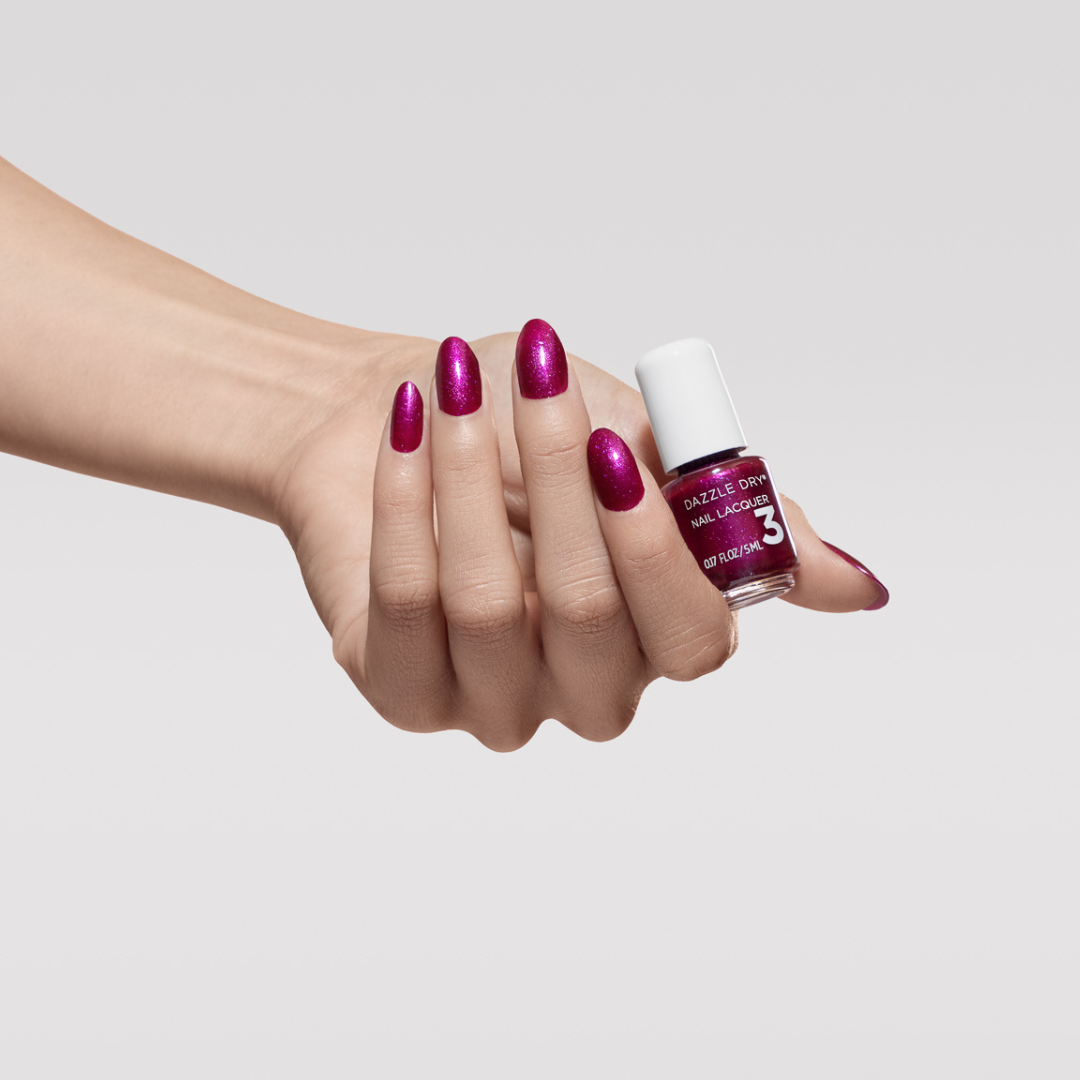 Hand with In Orbit painted on nails holding mini lacquer bottle