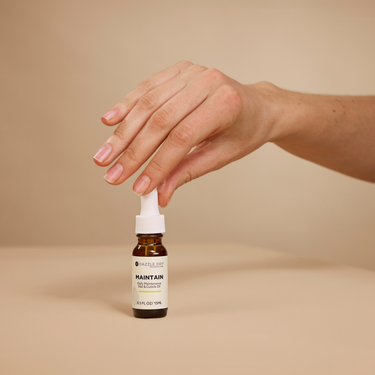 Hand holding a dropper bottle labeled 'Maintain' on a beige background