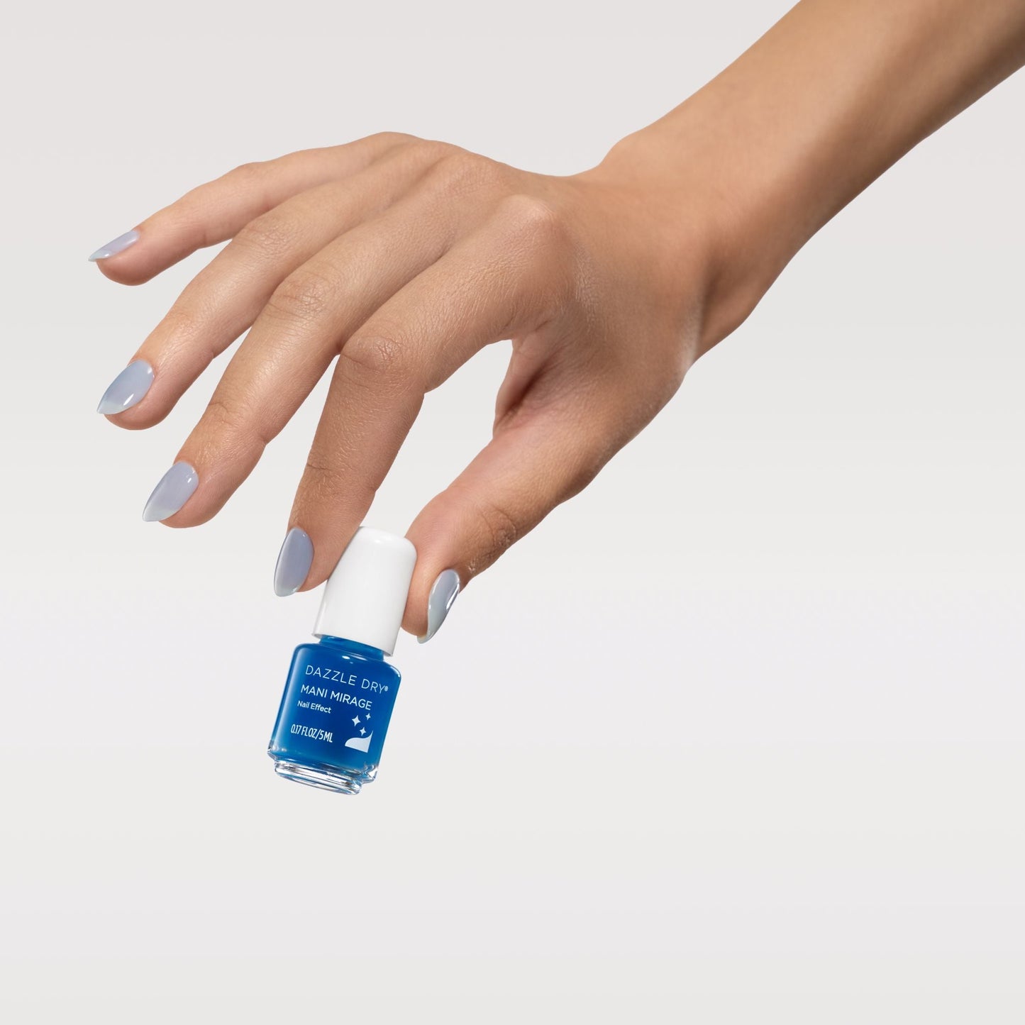 Hand holding a blue nail polish bottle with a light gray background