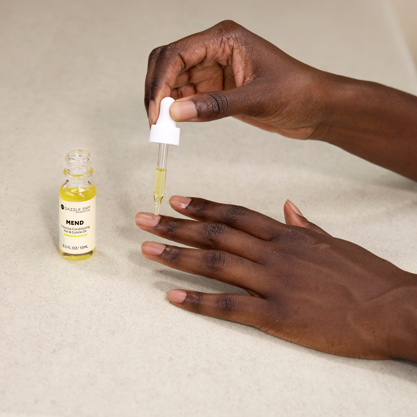 Hand holding a dropper with a bottle labeled 'Mend' on a beige background