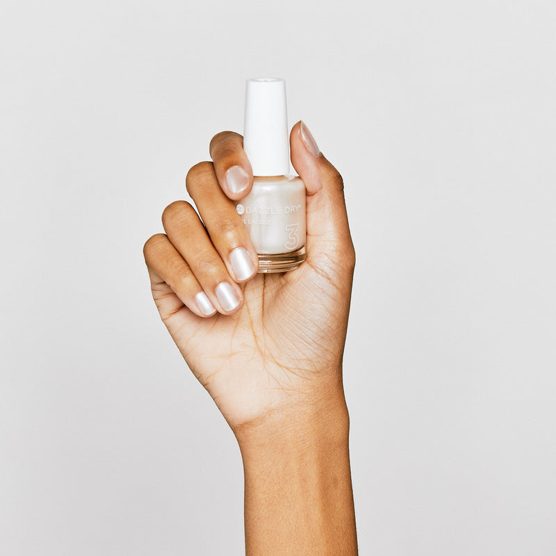 Hand with Pearl painted on nails holding nail lacquer bottle