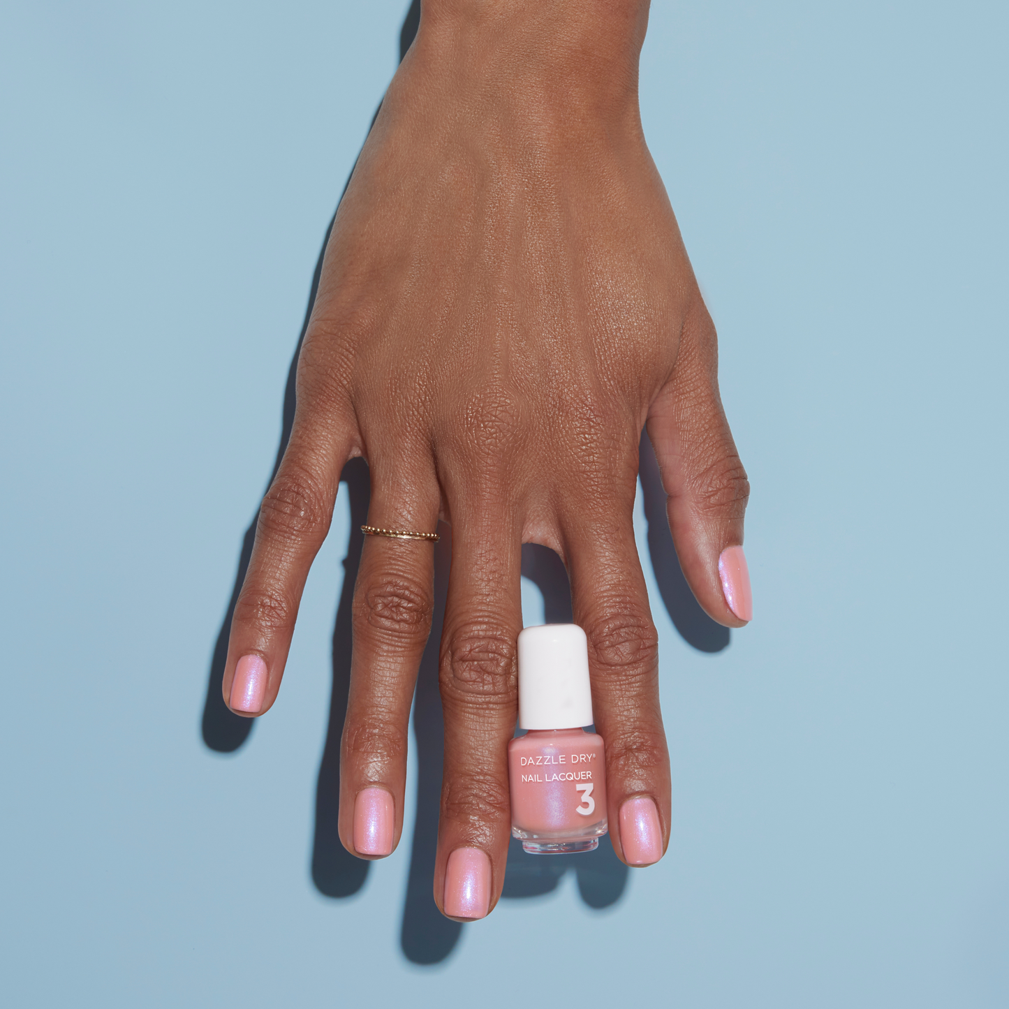 Hand with Milky Way painted on nails holding mini lacquer bottle