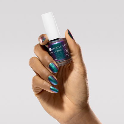 Hand with Nebula painted on nails holding lacquer bottle