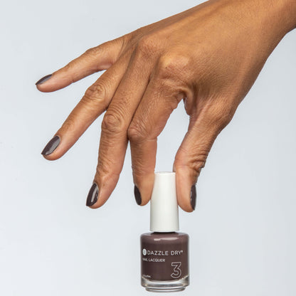 Hand with Rum Raisin painted on nails holding lacquer bottle