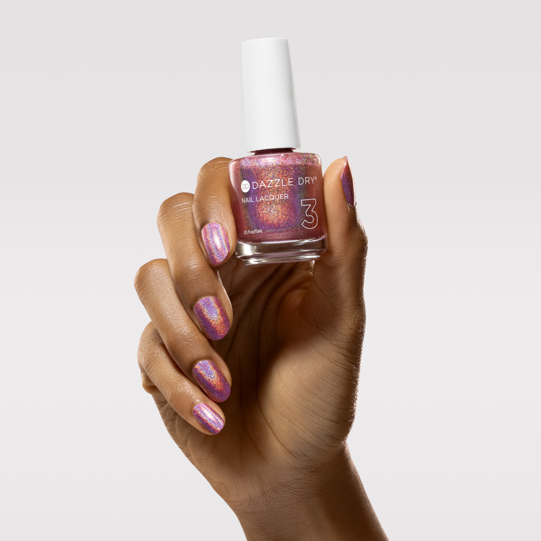 Hand with Supernova painted on nails holding lacquer bottle