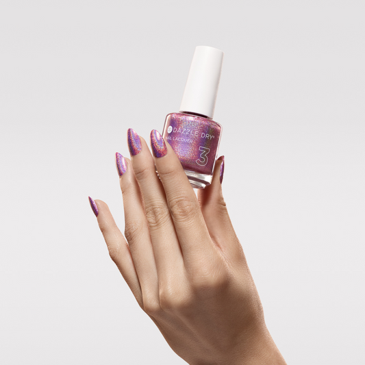 Hand with Supernova painted on nails holding lacquer bottle