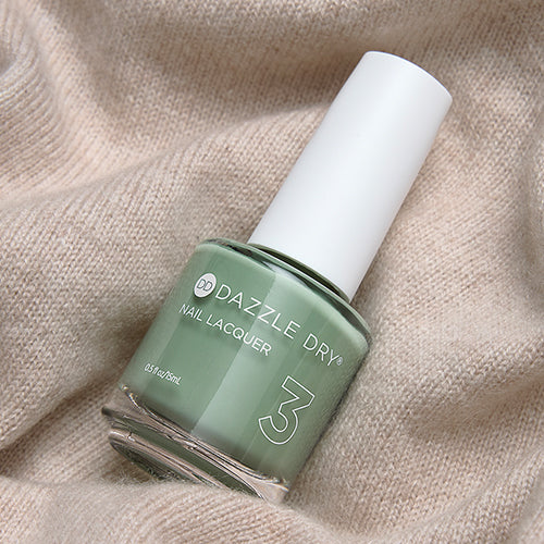 Dazzle Dry Cardigan nail lacquer in light green-cream shade displayed on top of a light cream sweater fabric.