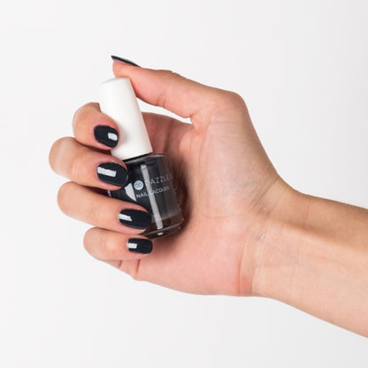 Hand with Joan's Armor painted on nails holding lacquer bottle