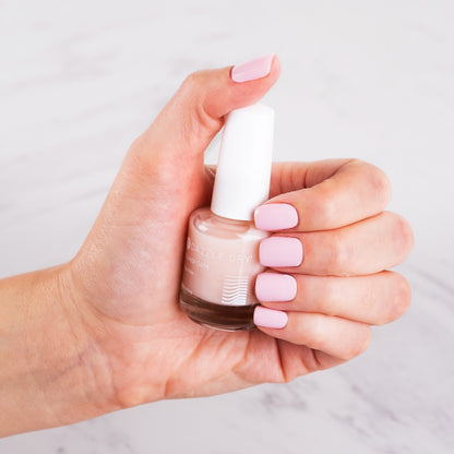 Hand with painted nails using Transform holding Transform bottle