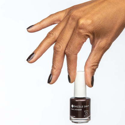 Hand with Merlot painted on nails holding lacquer bottle